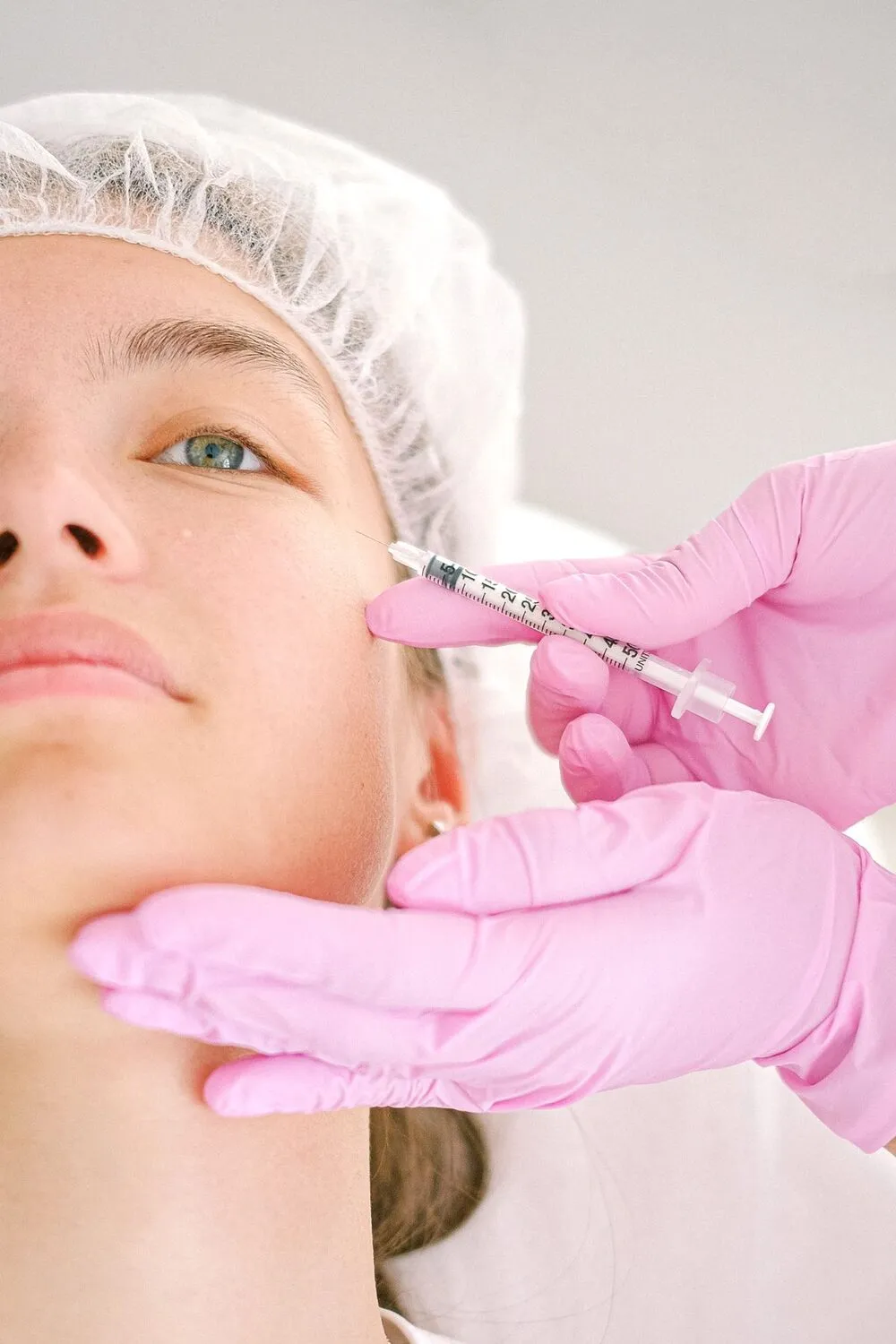 Facial aesthetic treatment with clinical gloves — illustrative of the forehead area