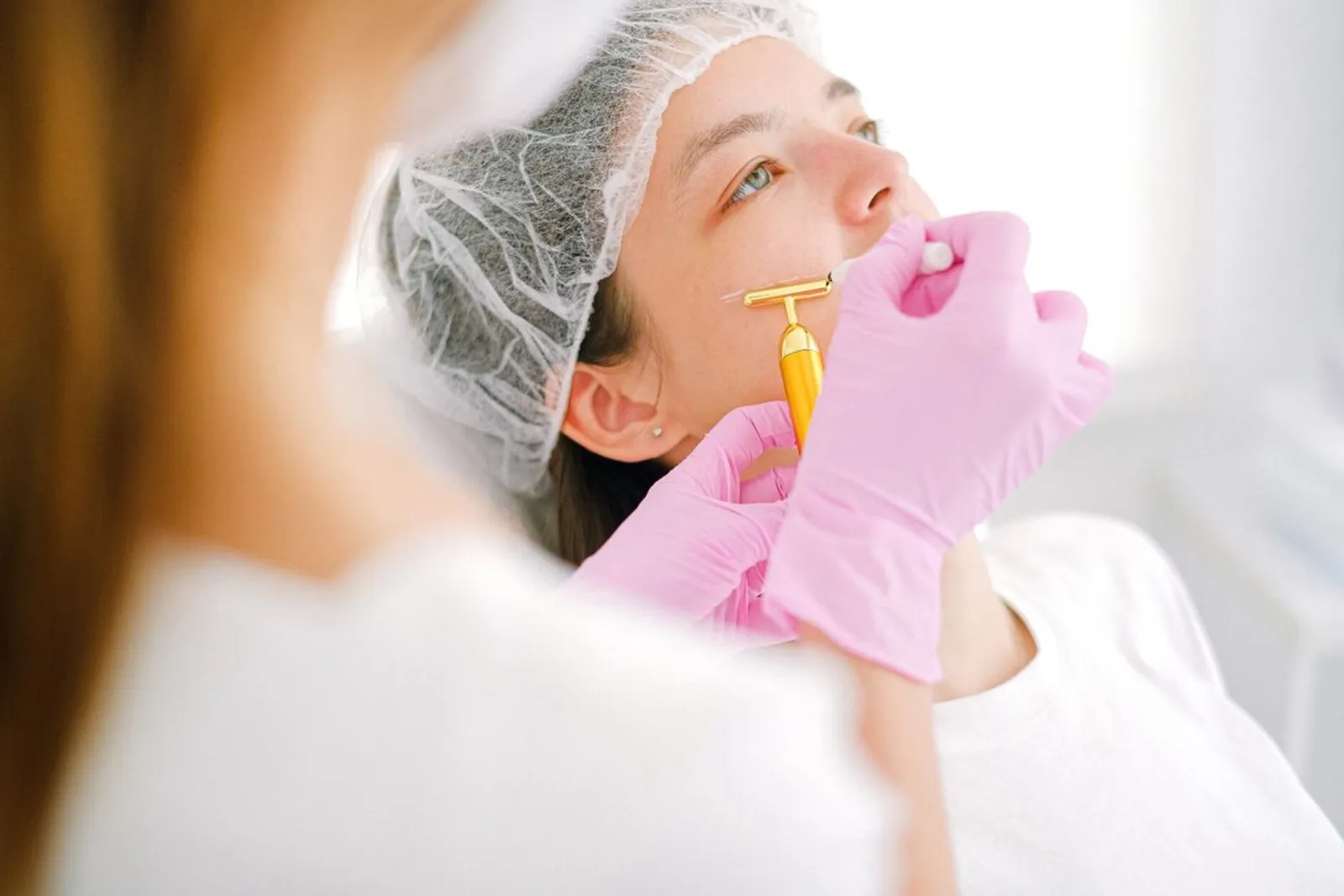 Facial aesthetic treatment with clinical gloves — illustrative of the eye area